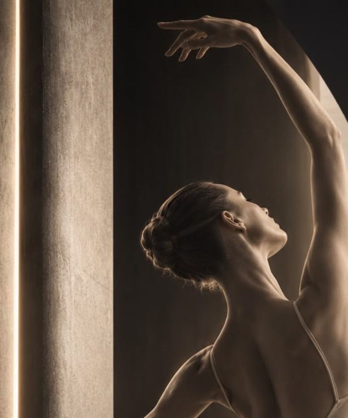 Danseuse en justaucorps clair, un bras levé en arc.