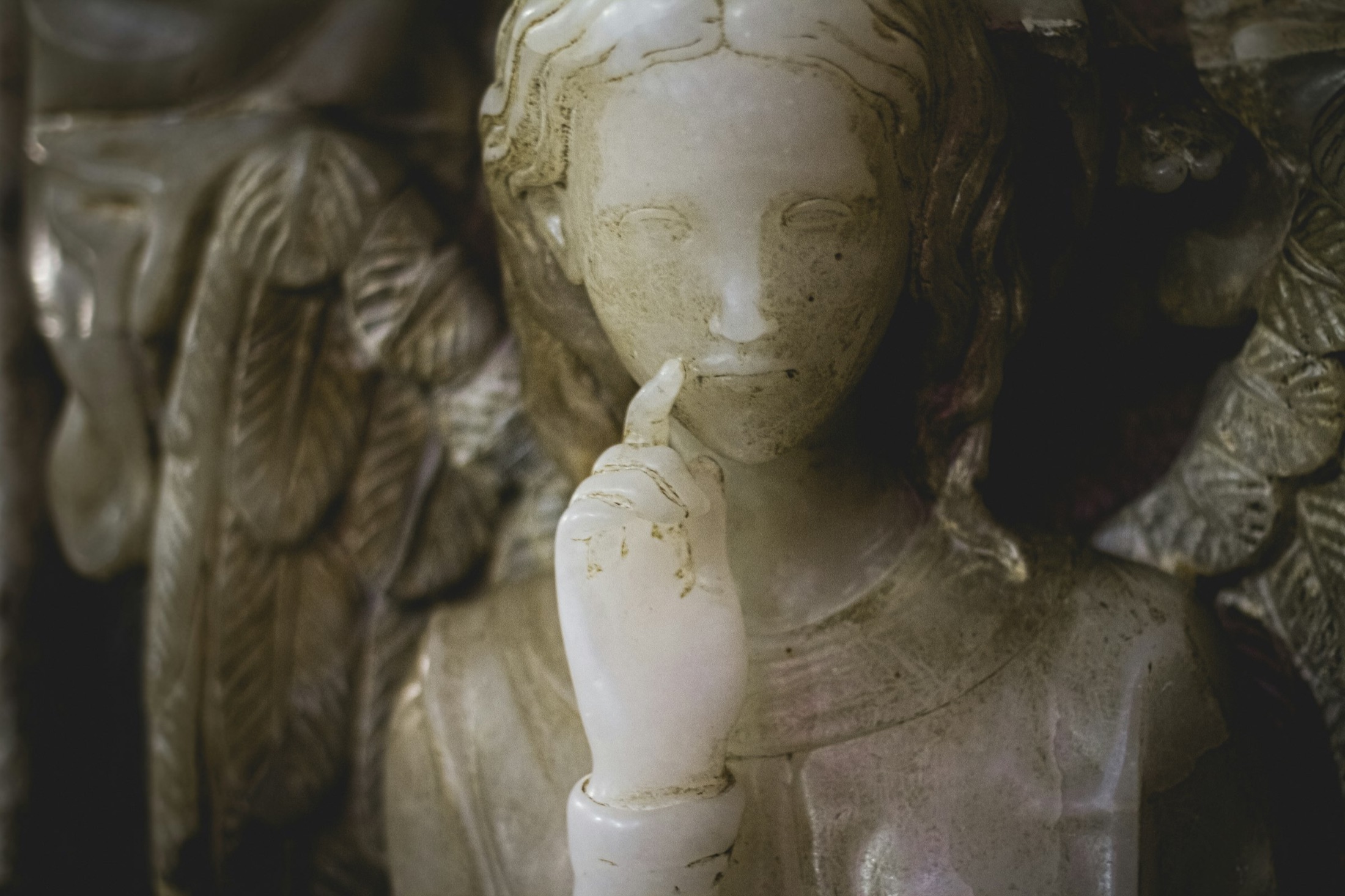 Statue d'ange en pierre, un doigt posé sur les lèvres.