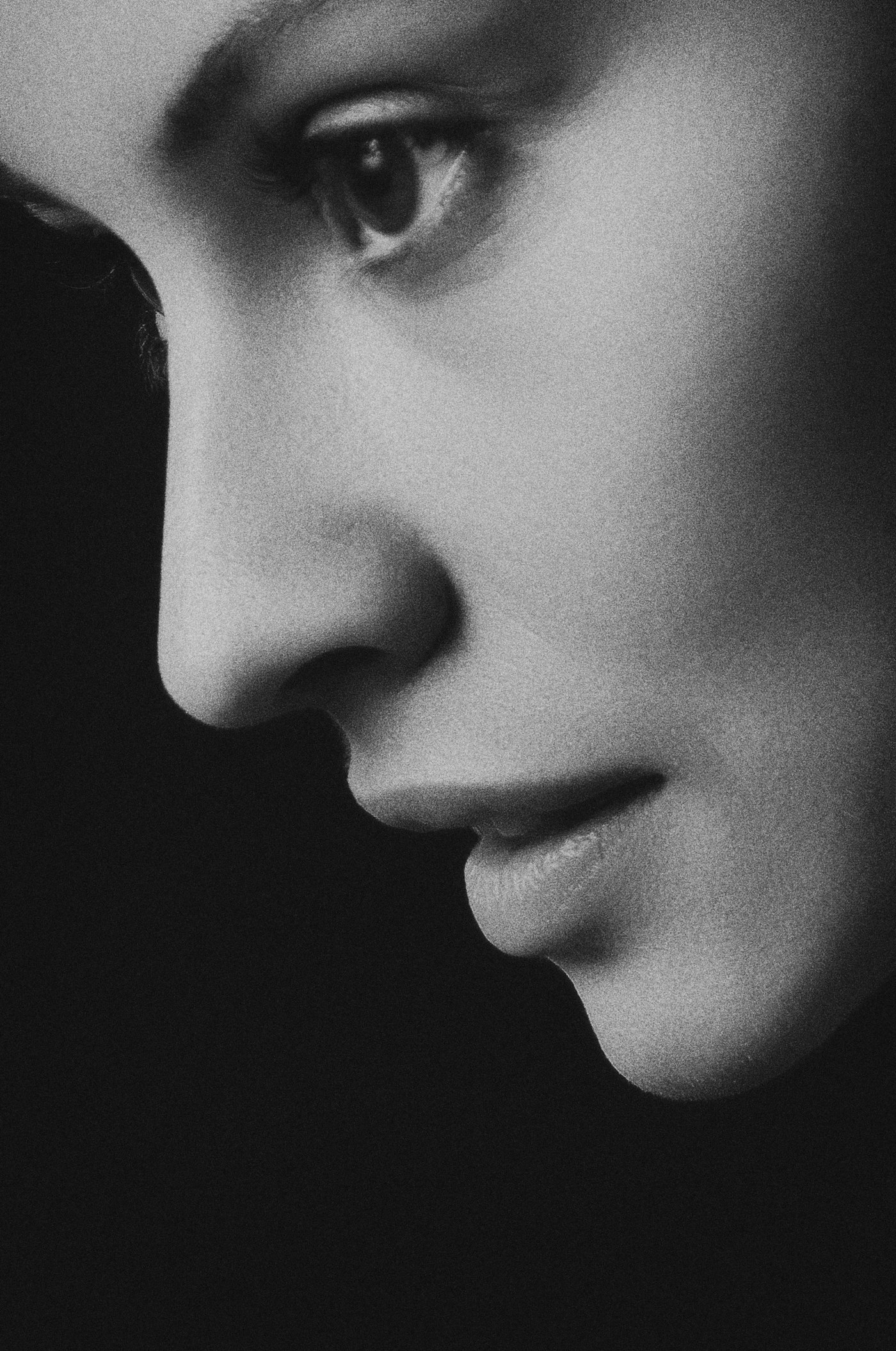 Profil de femme en noir et blanc, le regard baissé, lumière douce.