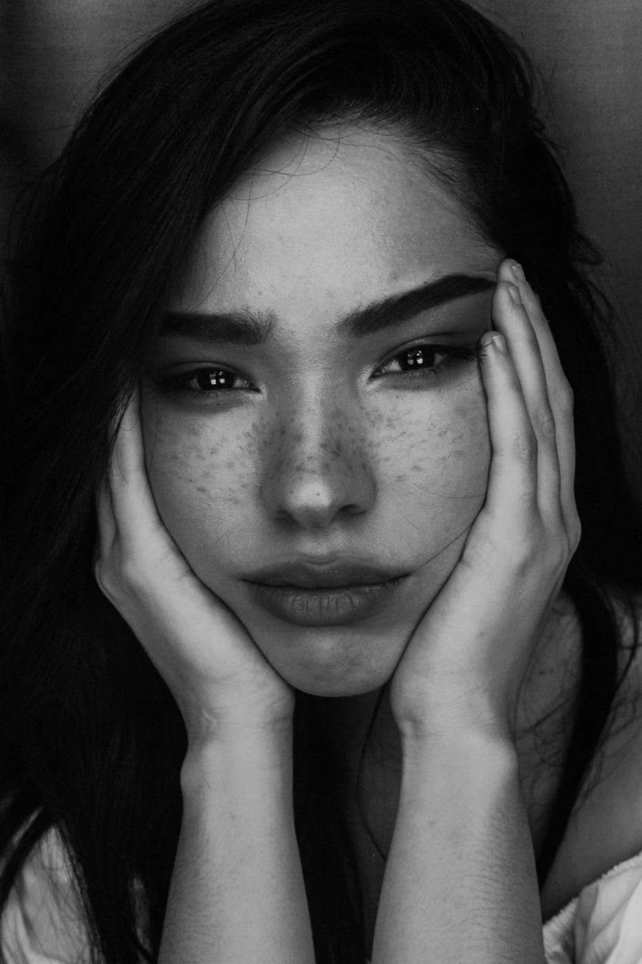 Jeune femme en noir et blanc, le visage entre ses mains.