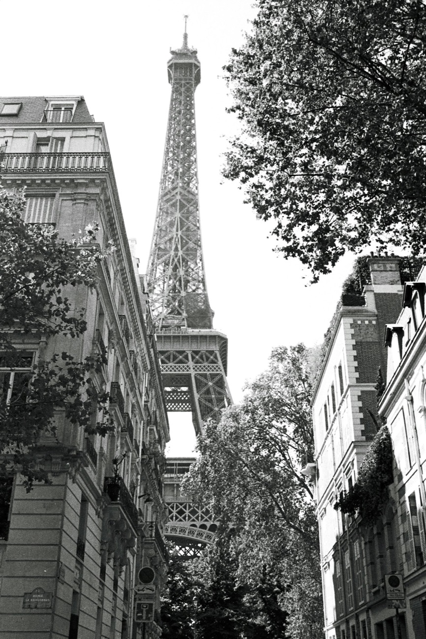 Rue haussmannienne à Paris avec la tour Eiffel au loin.
